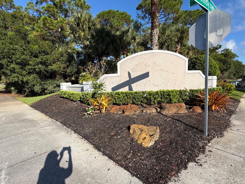 HOA community entrance monument with fresh mulch, trimmed hedges, and colorful plantings